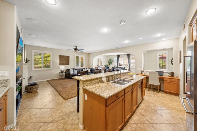 kitchen with light tile patterned floors, an island with sink, ceiling fan, high end refrigerator, and sink