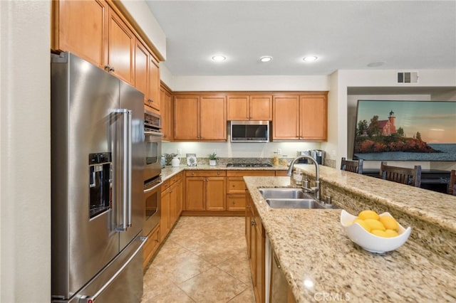 kitchen with light tile patterned floors, light stone countertops, stainless steel appliances, and sink