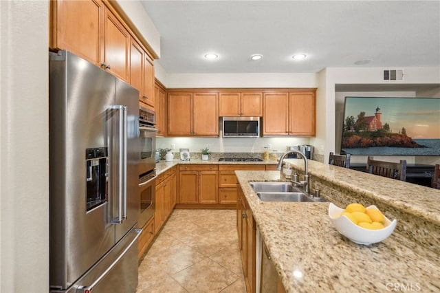 kitchen with recessed lighting, stainless steel appliances, a sink, visible vents, and light stone countertops