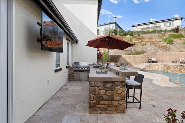 view of patio / terrace with an outdoor kitchen, grilling area, fence, outdoor wet bar, and a sink