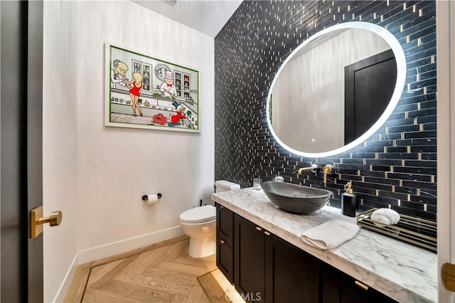 bathroom featuring tasteful backsplash, toilet, vanity, and baseboards