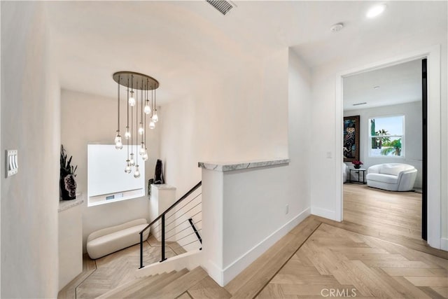 corridor with visible vents, an upstairs landing, and baseboards