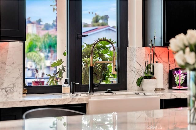 room details featuring light stone countertops, tasteful backsplash, and dark cabinets