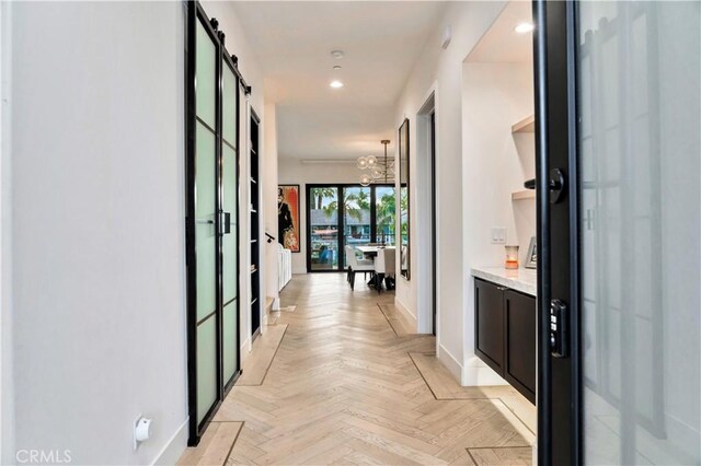 hallway featuring a barn door and light parquet flooring