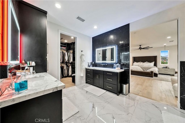 ensuite bathroom with visible vents, two vanities, ensuite bathroom, marble finish floor, and a ceiling fan