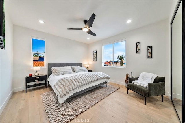 bedroom featuring light wood finished floors, multiple windows, and baseboards