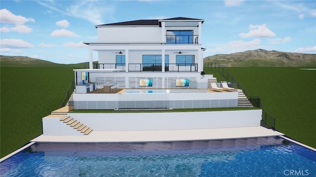 back of house featuring stucco siding, stairway, a mountain view, a balcony, and ceiling fan