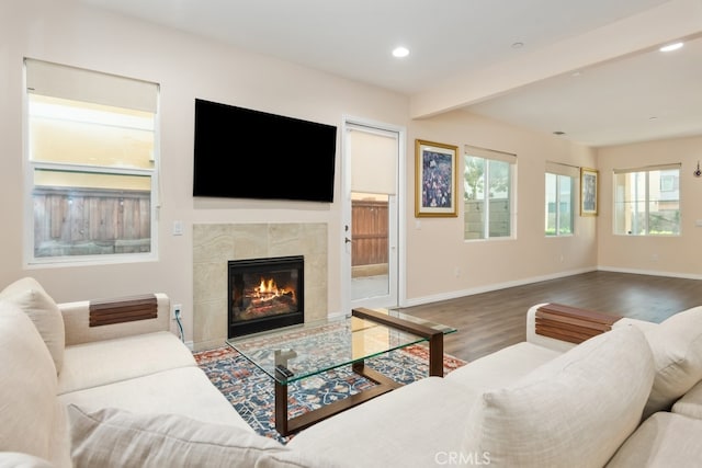 living room with beamed ceiling, a tile fireplace, and hardwood / wood-style floors