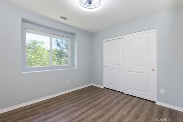 unfurnished bedroom with a closet and dark hardwood / wood-style floors