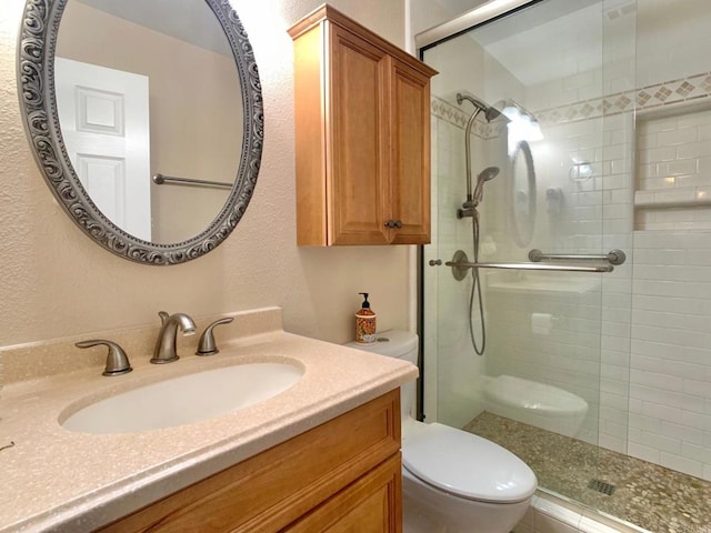 bathroom featuring vanity, a shower with shower door, and toilet