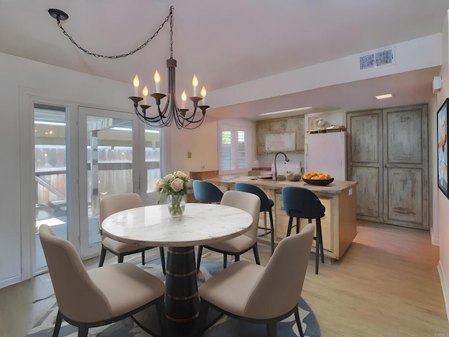 dining area featuring sink, a notable chandelier, and light hardwood / wood-style floors