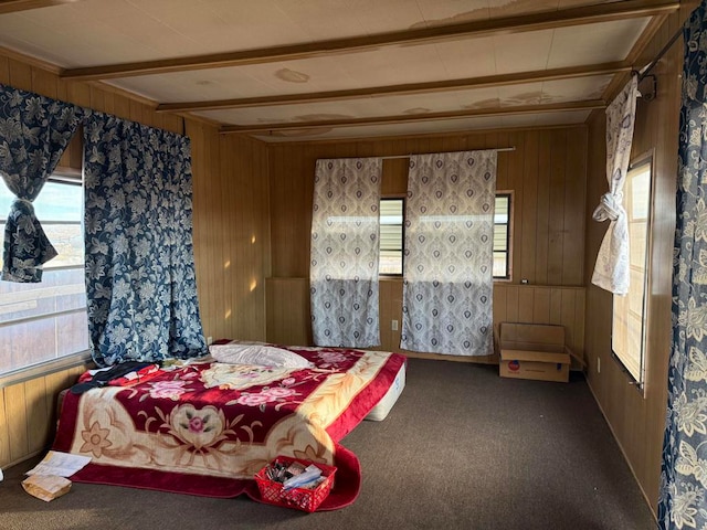 bedroom featuring beamed ceiling, carpet flooring, and wood walls