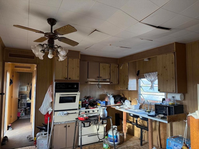 kitchen with light carpet, wood walls, oven, and ceiling fan