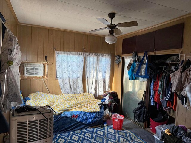 bedroom featuring wooden walls, carpet, a closet, and ceiling fan