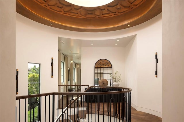 hallway featuring a towering ceiling, a raised ceiling, and parquet floors