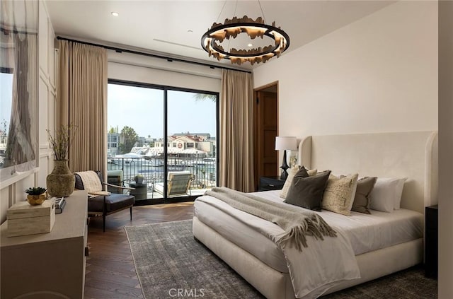 bedroom with dark hardwood / wood-style floors, access to exterior, and a water view