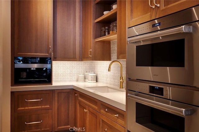 kitchen featuring backsplash, light stone counters, double oven, and sink