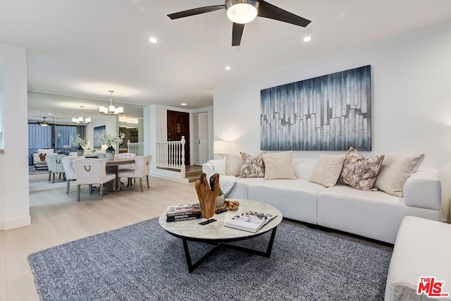 living room featuring hardwood / wood-style flooring and ceiling fan with notable chandelier