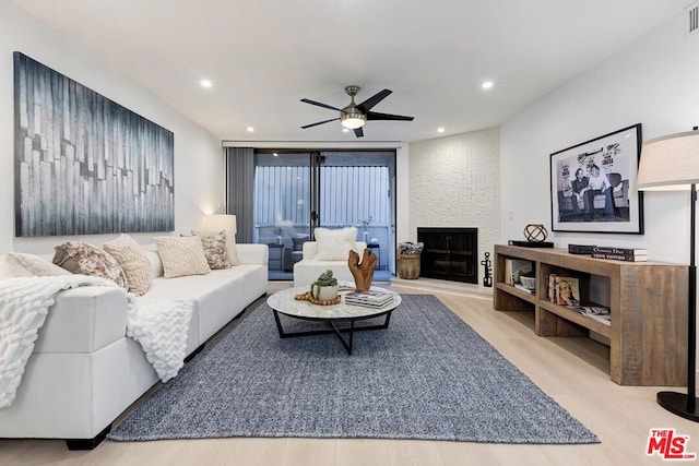 living room with a fireplace, a wall of windows, light hardwood / wood-style floors, and ceiling fan