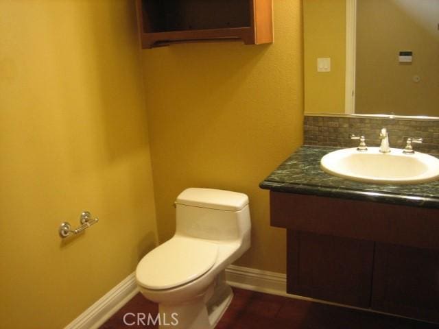 bathroom with toilet, vanity, and decorative backsplash