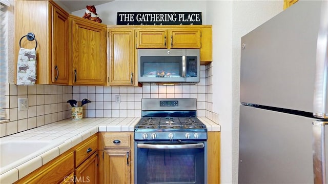 kitchen featuring tile counters, appliances with stainless steel finishes, and tasteful backsplash