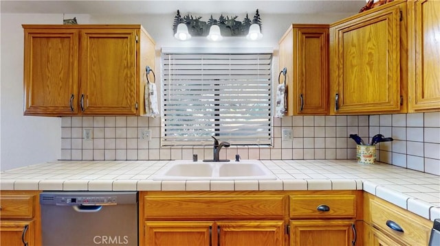 kitchen featuring stainless steel dishwasher, tile counters, sink, and tasteful backsplash