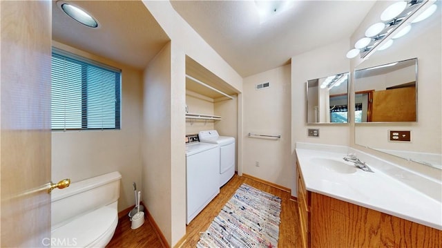 bathroom with vanity, vaulted ceiling, hardwood / wood-style flooring, washer and dryer, and toilet