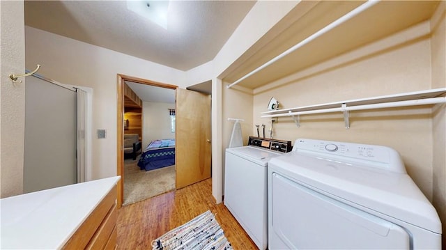 clothes washing area with washer and clothes dryer and light hardwood / wood-style floors