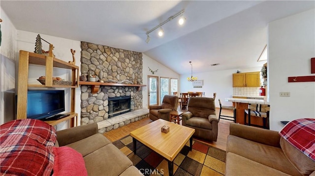 living room with hardwood / wood-style flooring, a stone fireplace, and lofted ceiling