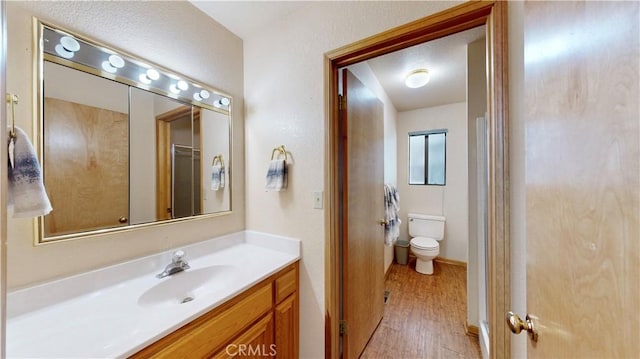 bathroom with hardwood / wood-style floors, vanity, and toilet