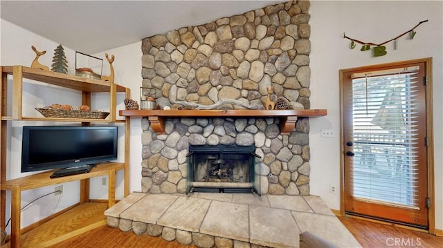 living room featuring a stone fireplace and light wood-type flooring