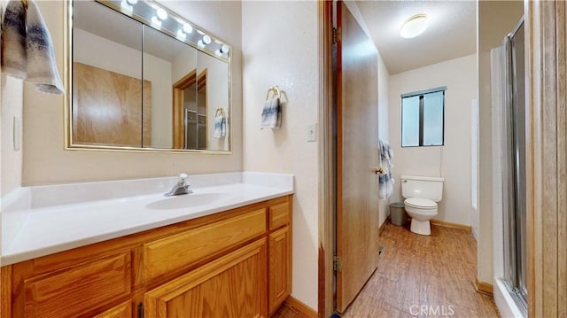 bathroom with hardwood / wood-style floors, vanity, toilet, and a shower