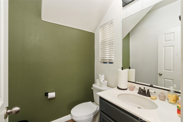 bathroom featuring vanity, toilet, and vaulted ceiling