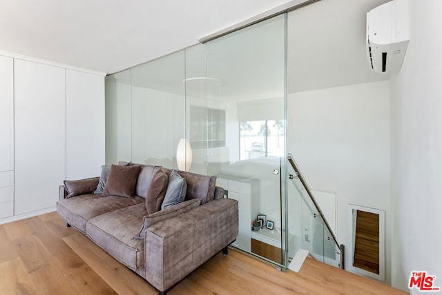 living room featuring a wall unit AC and light hardwood / wood-style flooring