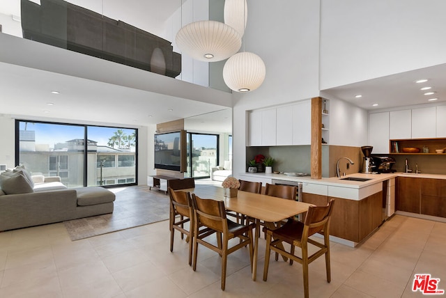 tiled dining room featuring a towering ceiling and sink