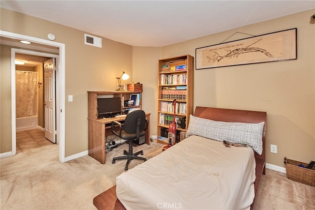 bedroom with ensuite bathroom and carpet flooring