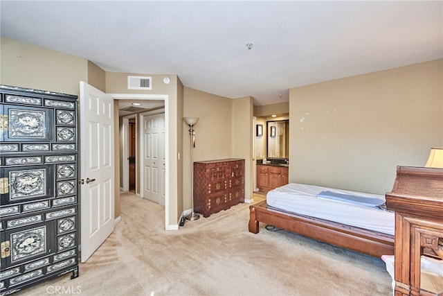 bedroom with connected bathroom and light carpet