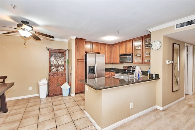 kitchen featuring kitchen peninsula, dark stone countertops, ornamental molding, sink, and appliances with stainless steel finishes