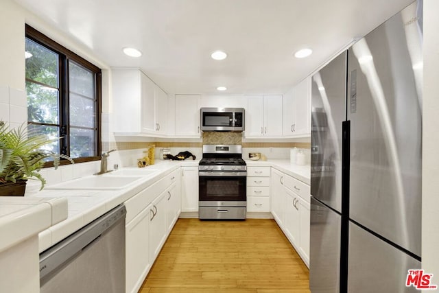 kitchen featuring white cabinets, stainless steel appliances, light hardwood / wood-style flooring, and sink