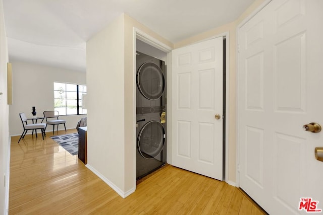 washroom with wood-type flooring and stacked washer / drying machine