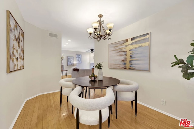 dining room featuring ceiling fan with notable chandelier and light hardwood / wood-style floors