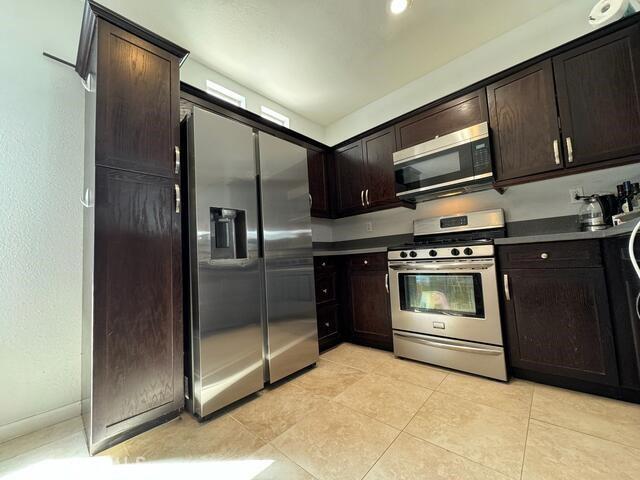 kitchen featuring light tile patterned flooring, appliances with stainless steel finishes, and dark brown cabinets