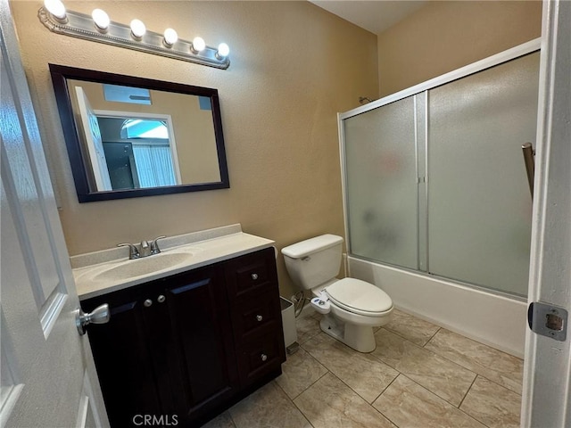 full bathroom with vanity, bath / shower combo with glass door, tile patterned floors, and toilet