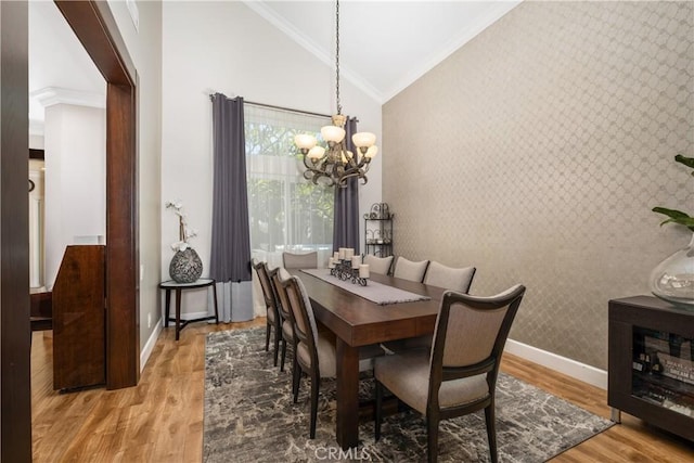 dining space with crown molding, hardwood / wood-style flooring, vaulted ceiling, and an inviting chandelier