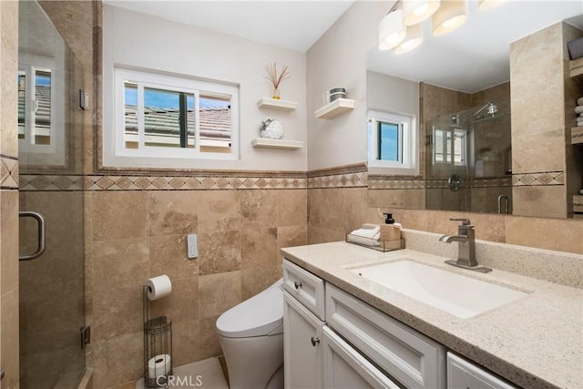 bathroom with tile walls, vanity, a shower with door, and toilet