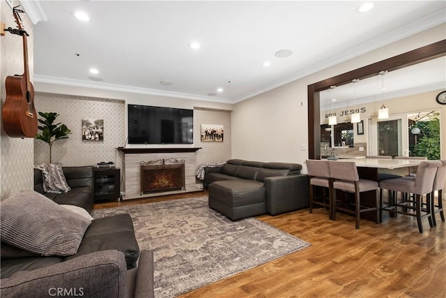 living room with crown molding, wood-type flooring, and a tile fireplace