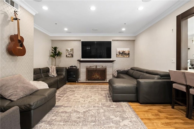 living room with hardwood / wood-style floors, crown molding, and a premium fireplace