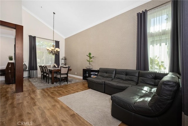 living room featuring crown molding, lofted ceiling, wood-type flooring, and a notable chandelier