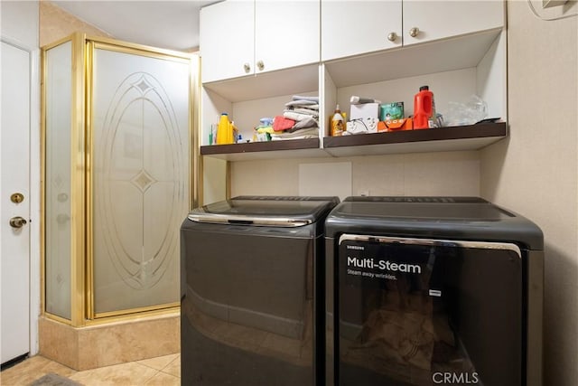 washroom with light tile patterned floors, washer and clothes dryer, and cabinets