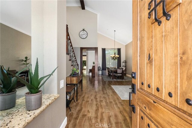 foyer featuring ornamental molding, lofted ceiling, hardwood / wood-style floors, and a notable chandelier